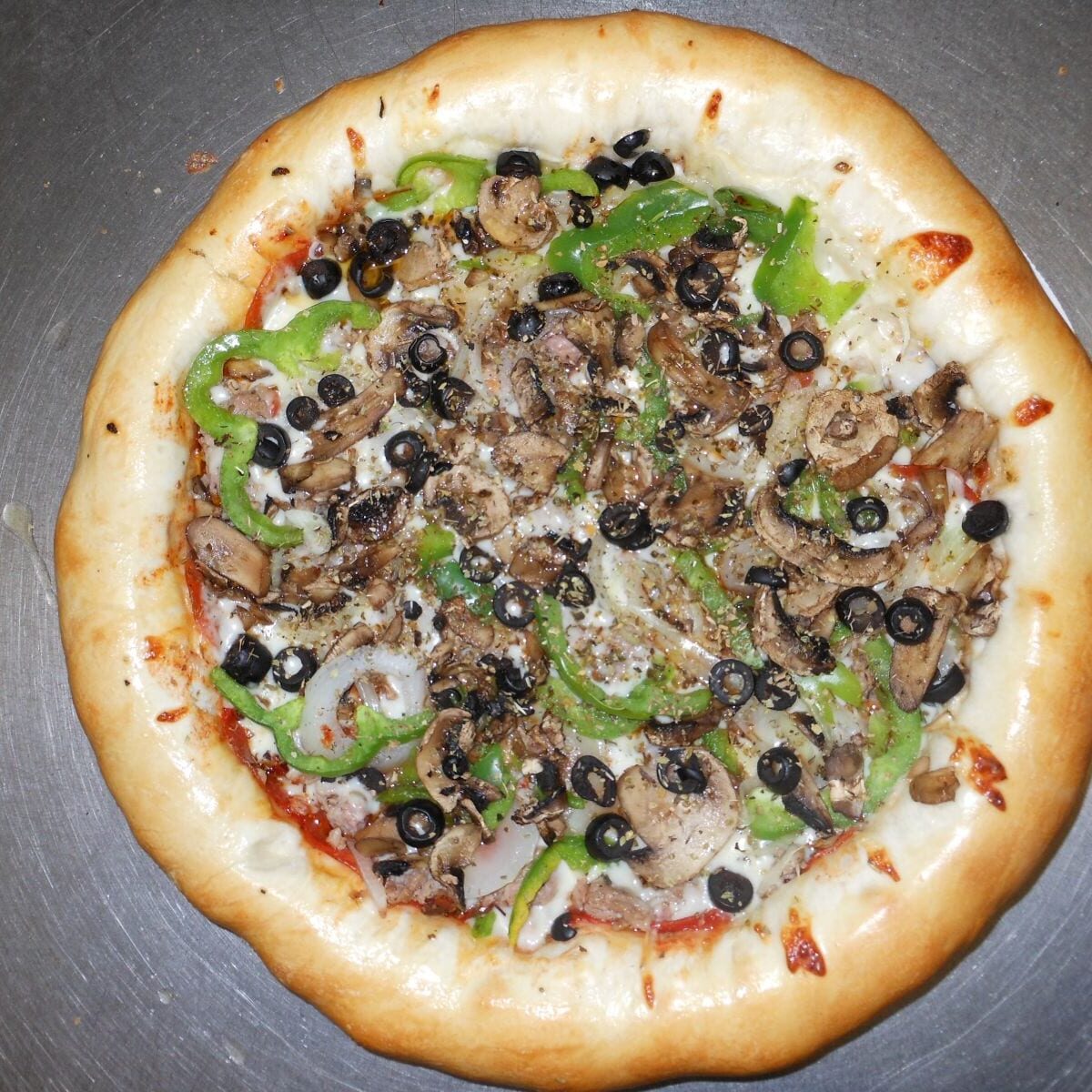 A pizza with black olives, mushrooms and green peppers.