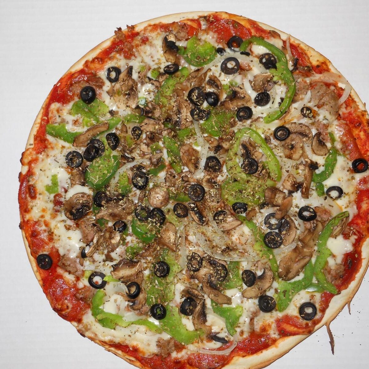 A pizza with mushrooms, green peppers and black olives.